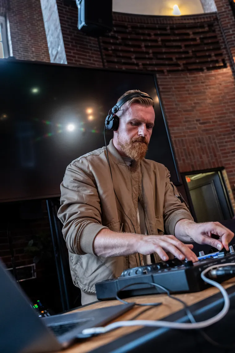 Dawid an der DJ Booth, Kopfhörer am Ohr, die Hände am Mischpult